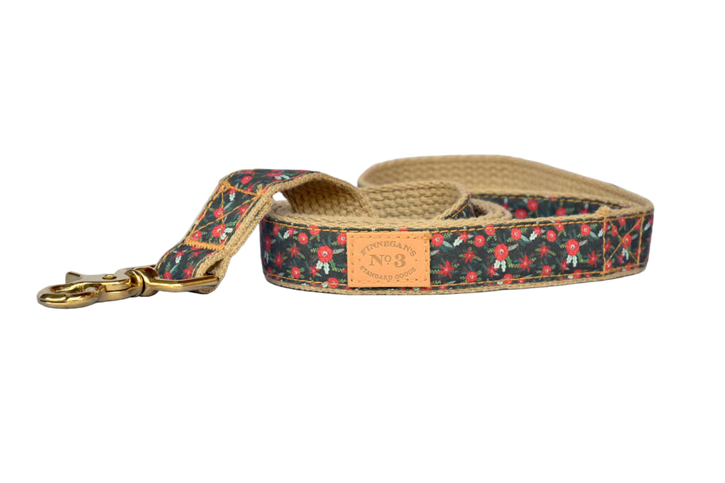 Dog leash with floral pattern and gold hardware on a wooden surface