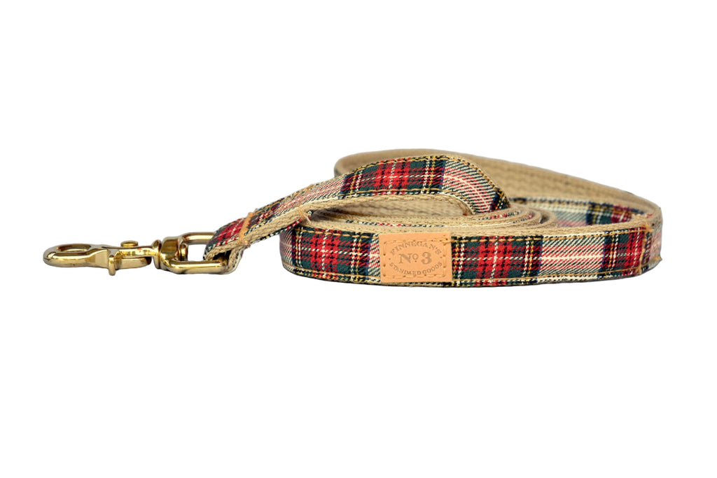 Plaid dog leash with gold clip on a gray wooden surface