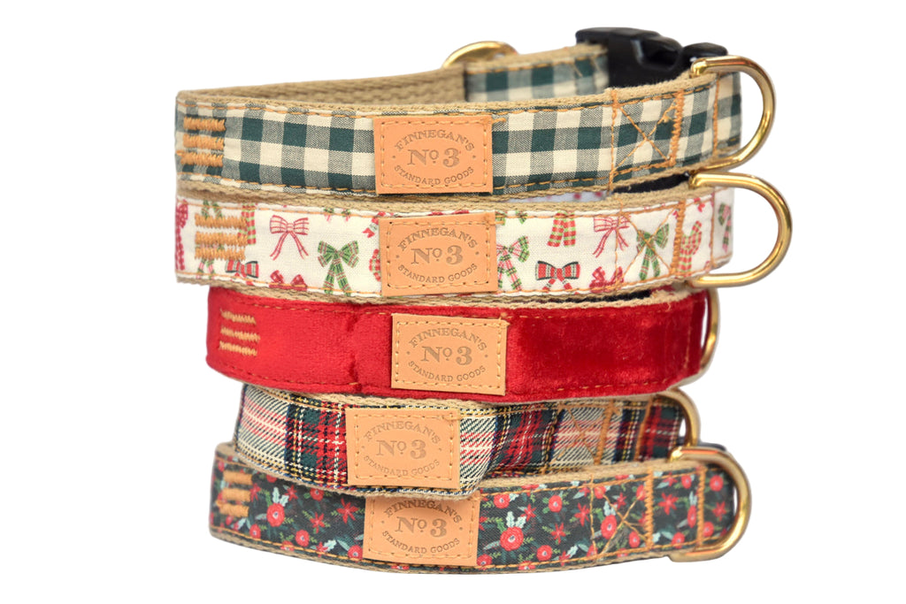Stack of four dog collars with different patterns on a light wooden surface.