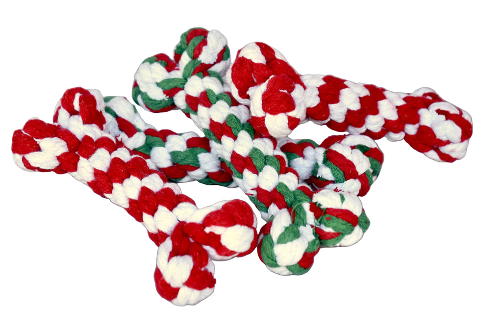 Red, white, and green braided dog toy on a wooden surface
